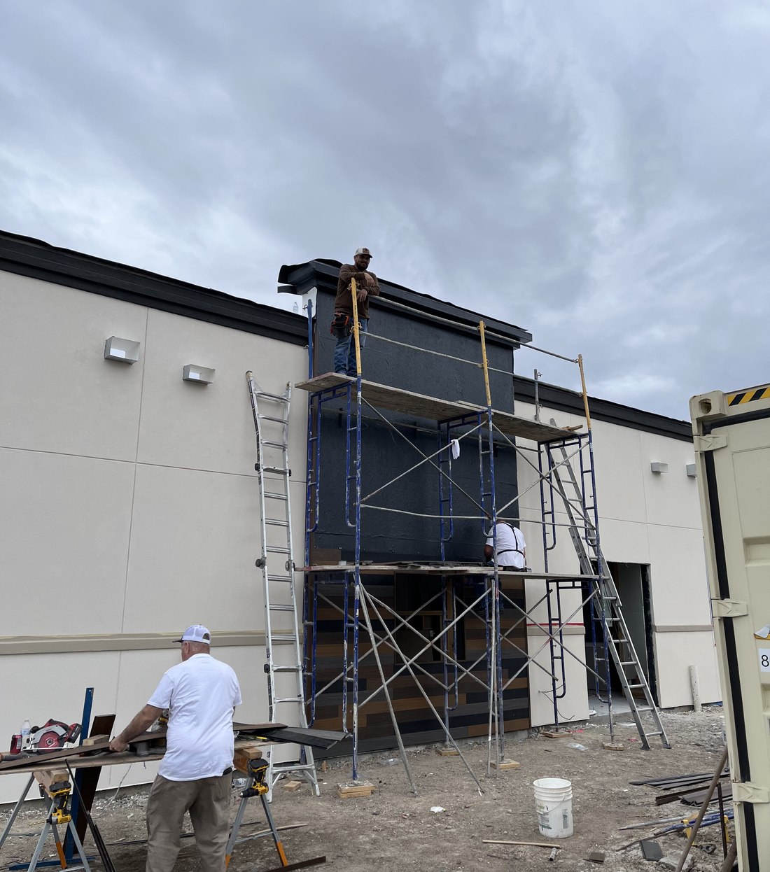 Crew installing facade panels from scaffolding